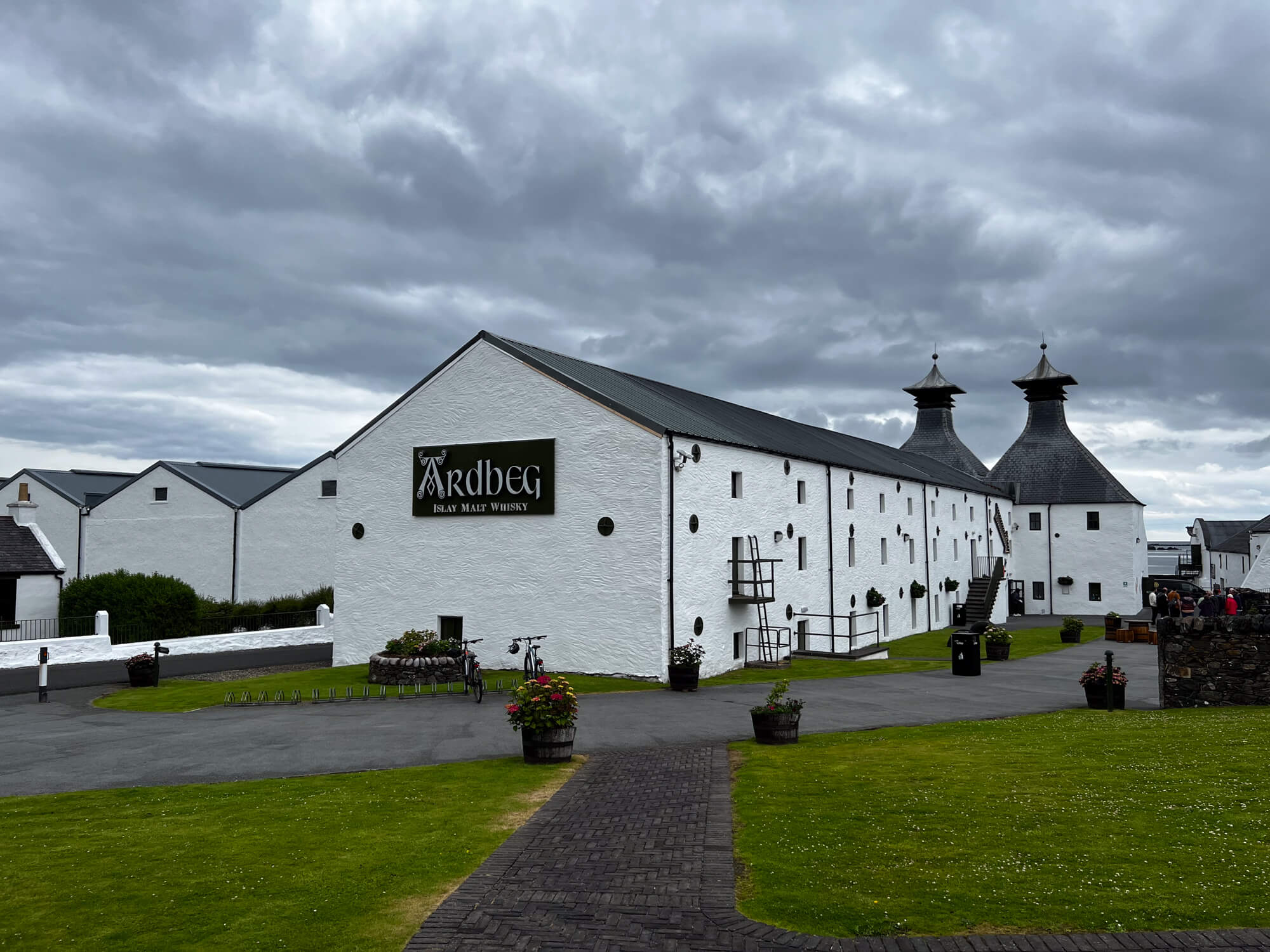 Ardbeg Trudernish whisky flessen op de voorgrond met de rotsige kustlijn van Islay op de achtergrond