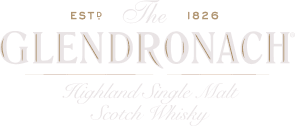 The GlenDronach sherry cask whisky flessen op de voorgrond met een mistige Schotse Highland-vallei op de achtergrond